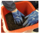 person with gloves leveling surface of contents in calibrated container